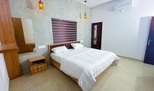 a bedroom with a white bed with a wooden headboard at Thushara Homestay in Kozhikode