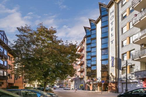 a building on a city street with a tree at Thomas Hotel Budapest in Budapest