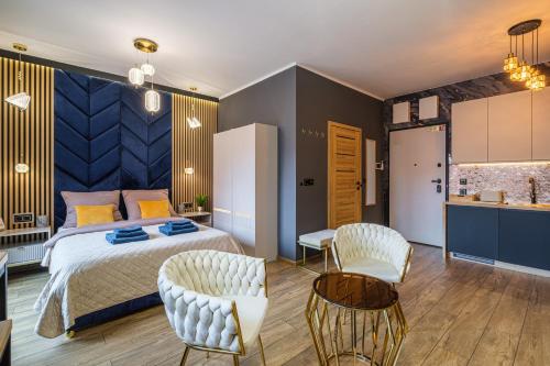 a bedroom with a bed and two chairs and a kitchen at Golden Eagle Luxury Apartment - Granary Island- Gdańsk Old Town in Gdańsk