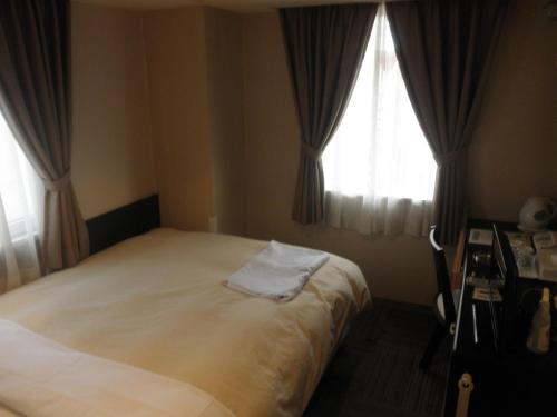 市原市にあるホスピタリティイン 八幡宿のベッドルーム1室(ベッド1台、窓2つ付)