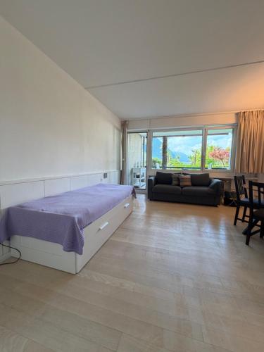 a large bedroom with a bed and a couch at Holiday on the Lake Lugano in Bissone