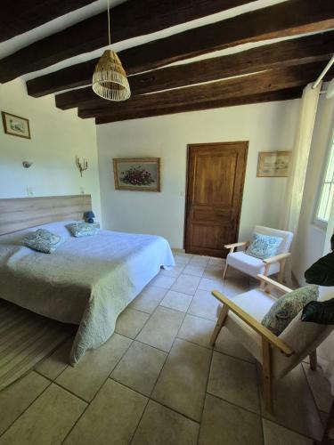 a bedroom with a bed and a chair in it at Le Moulin Garnier in Vernou-sur-Brenne