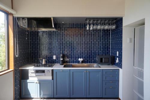 a kitchen with a sink and a blue tile wall at 海を望む東伊豆の一棟貸し ula Ocean-view private stay in Izu in Higashiizu