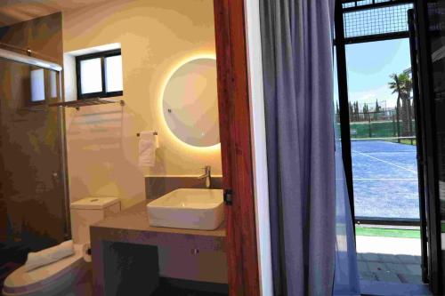 a bathroom with a sink and a toilet and a window at Hotel Camino Del Bosque Centro Pádel in Cholula
