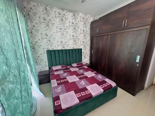 a small bedroom with a bed and a wooden cabinet at Pindora Stays in Ludhiana