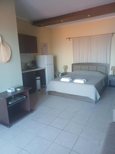 a bedroom with a bed and a table and refrigerator at Petani Beachside Accommodation in Vóvikes