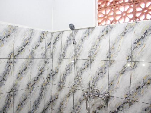 a shower in a bathroom with marble tiles at The Garden Sanctuary Homestay in Sidemen