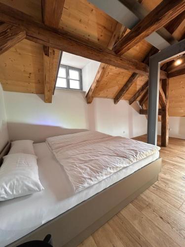 a white bed in a room with wooden ceilings at Platzl am Malteser in Amberg
