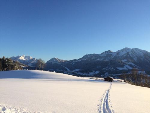 a snow covered field with mountains in the background at Ferienwohnung Alpenglück in Sankt Jakob in Haus