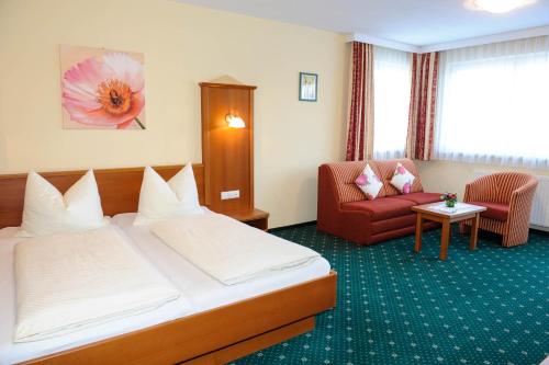 um quarto de hotel com uma cama e uma cadeira vermelha em Hotel Posauner em Sankt Veit im Pongau
