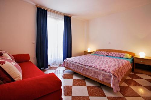 a bedroom with a bed and a couch and a window at Apartments AVA in Poreč