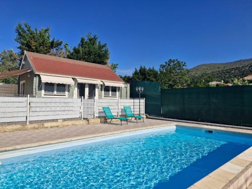 a swimming pool with two blue chairs and a house at Ribella in Appietto