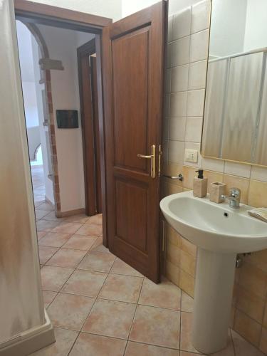 a bathroom with a sink and a wooden door at Casa Sant'Antonio in Orosei