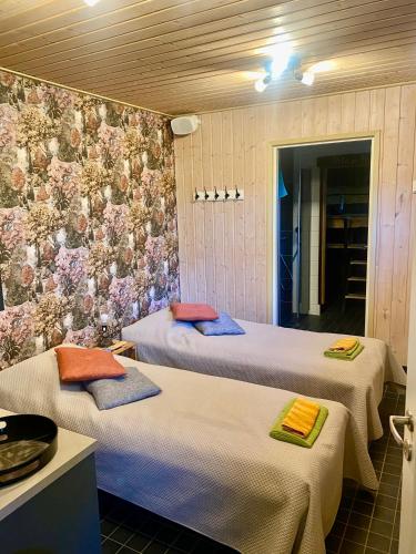 two beds in a room with flowers on the wall at Pollin Piha in Töfsala