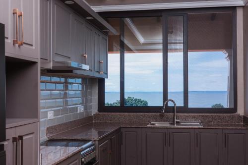 a kitchen with a sink and a large window at Hemingway's Hotel in Entebbe