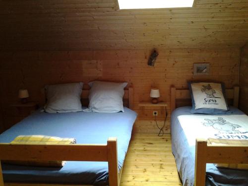 a bedroom with two beds in a log cabin at La Grange De L'Errance in Giron