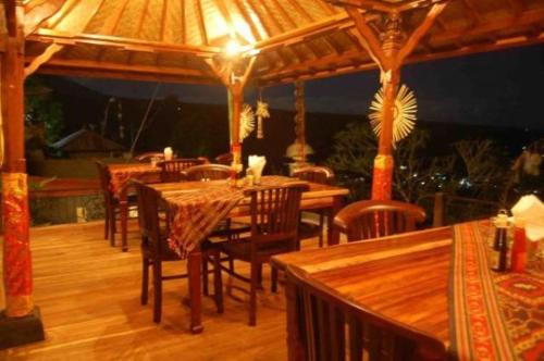 restauracja z drewnianymi stołami i krzesłami oraz parasolem w obiekcie Aditya Homestay w mieście Munduk