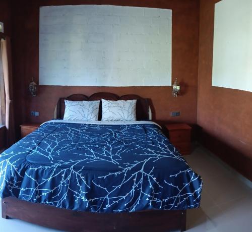 a bed with a blue comforter in a room at Tetebatu Sunrise Homestay in Tetebatu