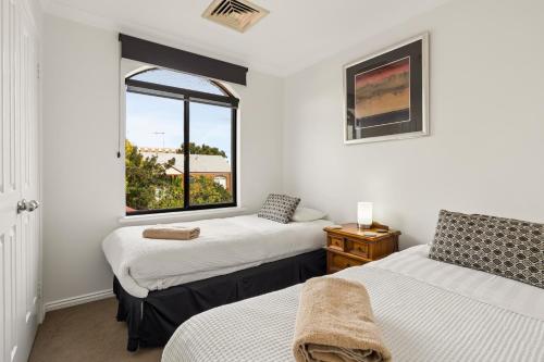 two beds in a room with a window at Group stays for Friends Families Weddings and Events Walkable to Fremantle and attractions Super Spacious with garden and courtyard and balcony and parking for 2 cars Sleeps 6 3BD 3BR in Fremantle