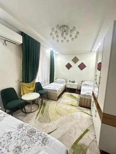 a hotel room with two beds and a table and chairs at Sultan Saray in Osh