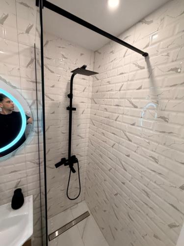 a shower in a bathroom with a white brick wall at Modern Panoramic View Apartament in Sighetu Marmaţiei