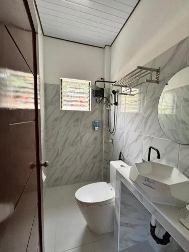a bathroom with a white toilet and a sink at SabinaGateway Suites in Panglao Island