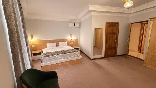 a hotel room with a bed and a chair at The Garden of Shaherezade in Bukhara