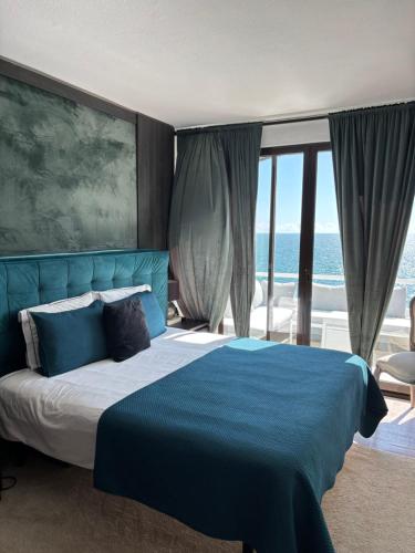 a bedroom with a blue bed with a view of the ocean at Bela Vista Suites in Carvoeiro