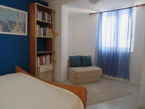 a bedroom with a bed and a chair and a book shelf at Mali raj in Stara Novalja