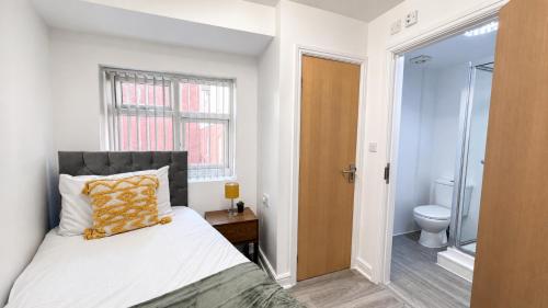 a bedroom with a bed and a bathroom with a toilet at Sangha House - Ensuite Rooms with Shared Kitchen Facilities in Leicester