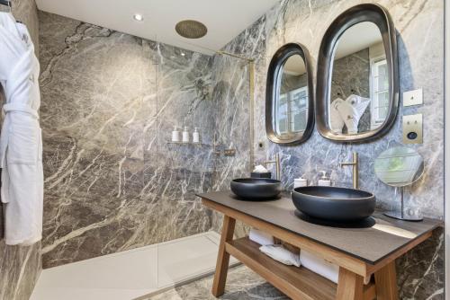 a bathroom with two sinks and two mirrors at Château de la Gaude in Aix-en-Provence