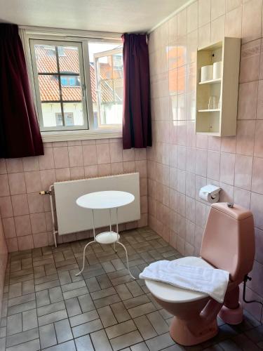a bathroom with a toilet and a table and a window at Värdshuset Hwitan in Falkenberg
