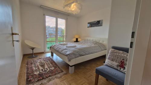 a bedroom with a bed and a chair and a window at Sunny Place Geneva 15 min Train in Versoix