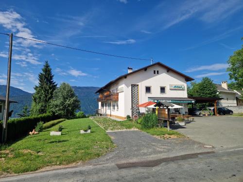 a white building with a grassy yard next to a street at Ferienwohnung Andritsch in Sankt Georgen im Gailtal