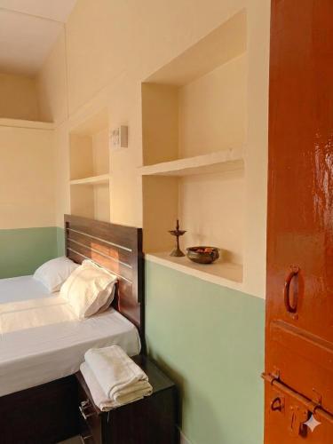 a bedroom with two beds and a cross on a shelf at Shristays in Varanasi