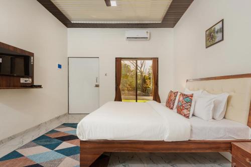 a bedroom with a large white bed and a window at Mango Serene by Roamigo in Karjat