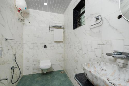a bathroom with a tub and a toilet and a sink at Mango Serene by Roamigo in Karjat