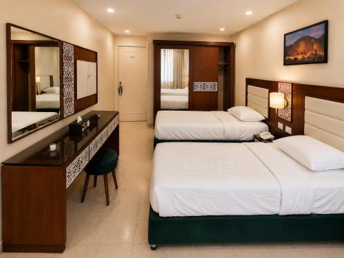 a hotel room with two beds and a desk at Karnak Hotel Luxor in Luxor