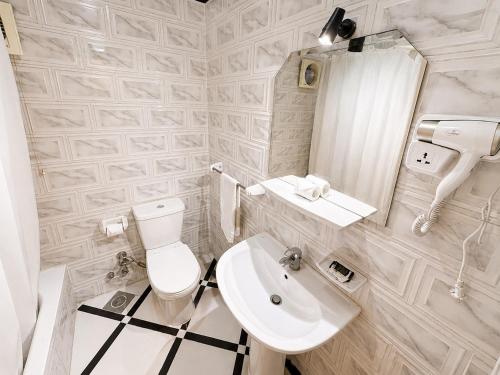 a white bathroom with a toilet and a sink at Karnak Hotel Luxor in Luxor