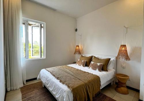 a bedroom with a bed with two lamps and a window at Little Palm Penthouse in Cap Malheureux
