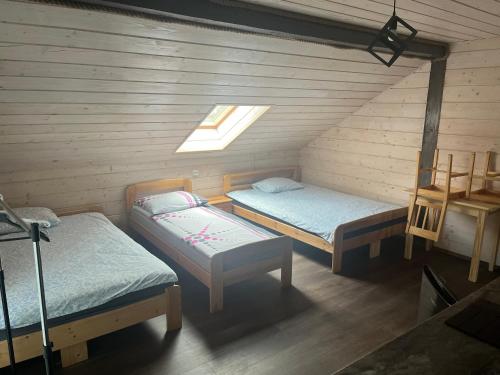 an attic room with two beds and a window at Noclegi Zakątek in Okuninka