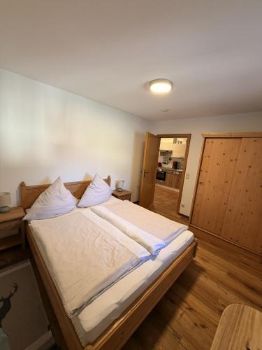 a bedroom with a large bed with white sheets at Ferienwohnungen Größwang in Bischofswiesen