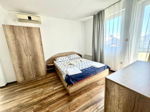a bedroom with a bed and a large window at Къща за гости ПЕРФЕКТО in Chernomorets