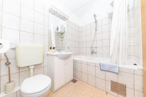 a bathroom with a toilet and a sink and a tub at Apartmani Villa Biočić in Split