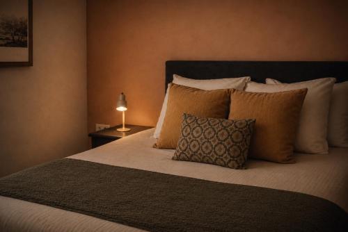 a bedroom with a bed with pillows and a lamp at Hoeve Verdre - De Knechtenwoning in Heers