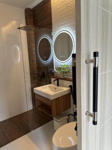 a bathroom with a sink and a toilet and two mirrors at Beas Boutique House Khlong Dow in Ko Lanta