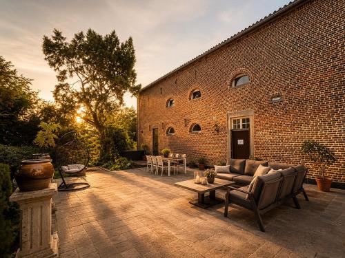 a patio with a couch and a brick building at Hoeve Verdre - De Knechtenwoning in Heers