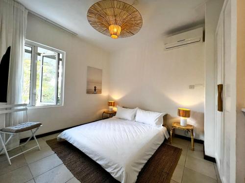a bedroom with a white bed and a window at Little Palm Studio in Cap Malheureux