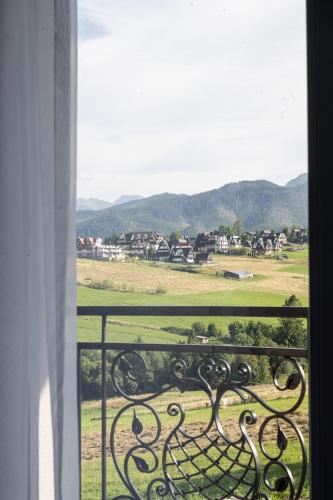 a window with a view of a field and mountains at Sądelski Dwór Medical & SPA in Zakopane