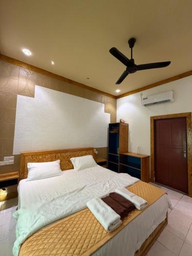 a bedroom with a large bed with a ceiling fan at Zora Beach Inn Mathiveri in Mathiveri